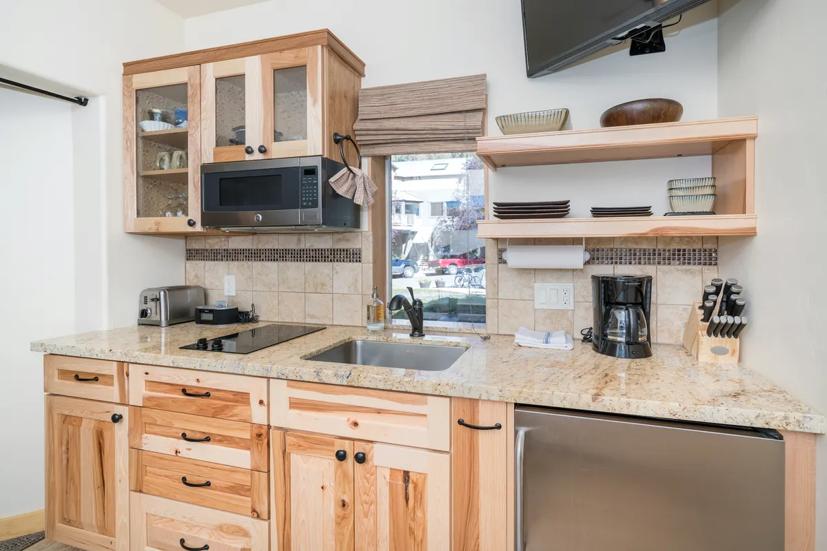 This image showcases a cozy and modern kitchenette with visible cabinets, a sink, countertop space, a microwave, and a coffee maker. The arrangement is compact yet functional, ideal for prepping breakfast or light meals. The inviting setup suggests a space that's easy to navigate and use, perfectly aligning with the section's emphasis on practicality and comfort.